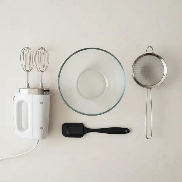 Essential equipment for making homemade butter, including a hand mixer, deep bowl, strainer, and spatula.