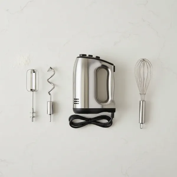 Various attachments for an electric hand mixer, including beaters, dough hooks, and a whisk, laid out.