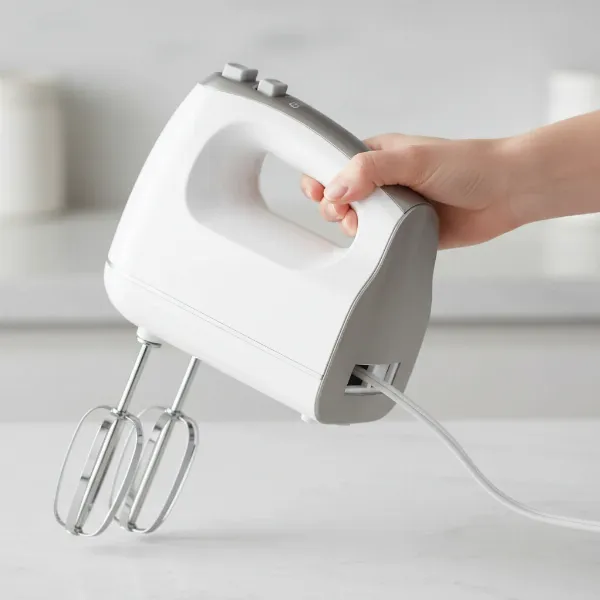 A hand mixer demonstrating its retractable cord mechanism, showing the cord winding into the appliance.
