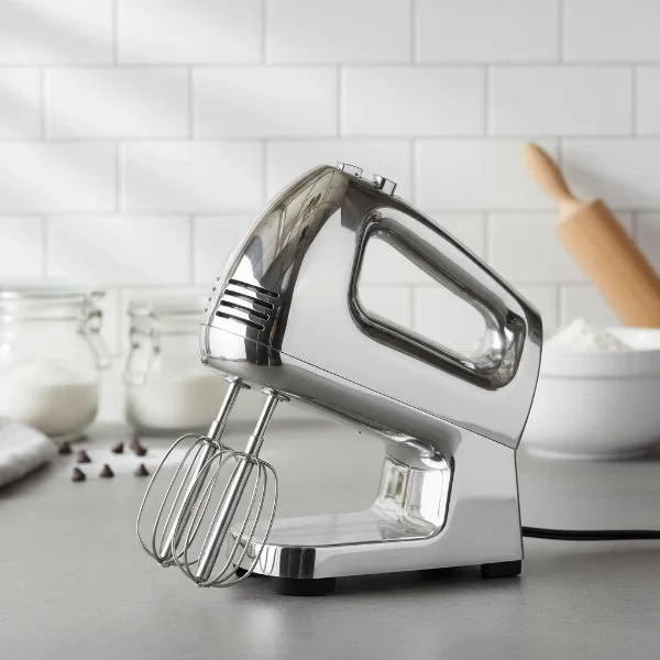 A close-up of a sleek, modern stainless steel hand mixer with a polished finish.